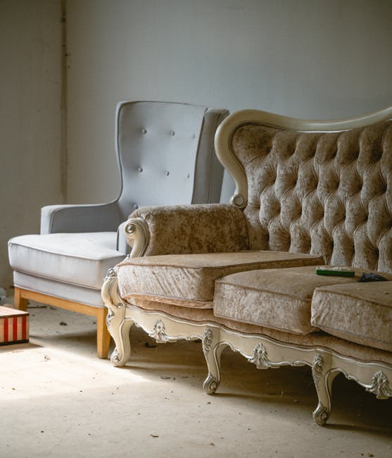 A large, L-shaped sofa with a modern design situated in a well-lit interior space. The sofa is upholstered in light grey fabric with a soft, textured finish, and features a series of matching cushions