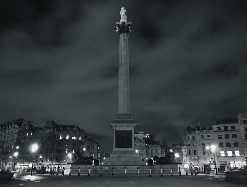 The image shows Trafalgar Square in Central London with a prominent neoclassical building featuring a large central dome, columns, and orange banners visible on the facade. In the foreground, a public